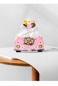 Detailweergave van roze trouwauto snoepdoosje met bloemenprints en wit satijnen strikje