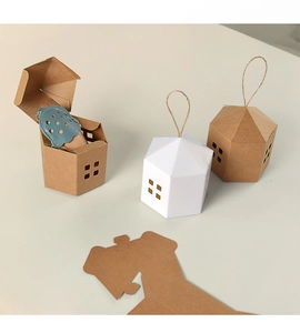 Detail of house-shaped gift boxes in white and kraft paper with rustic jute handles