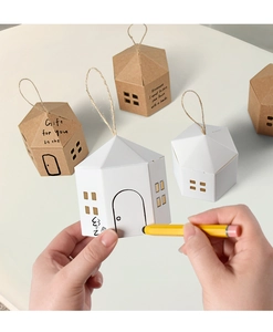 Detail of white house-shaped paper gift box being hand-drawn with a pencil for DIY