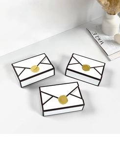 Three elegant envelope gift boxes with black borders and gold wax seals on a white desk