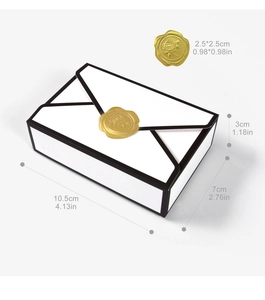 Detailed view of a white envelope candy box with black edges and gold rose seal sticker