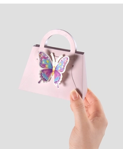 Macro detail of a small pink handbag-shaped gift box with a colorful butterfly held by hand