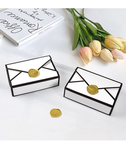Detail of minimalist black and white envelope candy boxes with gold wax seal for weddings