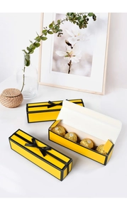 Macro view of a long yellow rectangular gift box showing 4-piece chocolate capacity