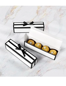 Close-up of long rectangular white gift box with black ribbon and four chocolates