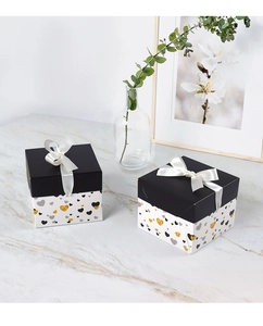 Detail of square gift boxes with heart patterns, white ribbon bows and marble surface