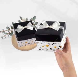 Square gift box with black lid and white bow featuring a glitter heart pattern detail