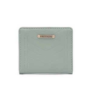 Close-up of mint green wallet featuring V-shaped chevron quilting and golden metal nameplate
