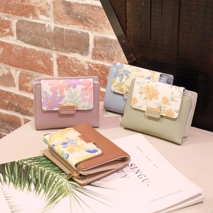 Close-up of small PU leather wallets featuring floral prints and metal zipper details