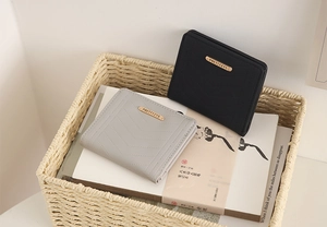 Close-up of quilted PU leather wallets in grey and black with gold logo plaque details