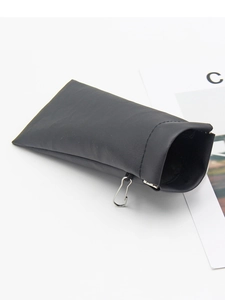 Detail of black leather glasses case with metal hook and fine stitching on white surface
