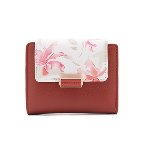 Detail of a brick red small wallet with floral print white flap and golden metal lock
