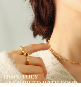 Detail of 18K gold-plated stainless steel spiral ring and minimalist chain necklace