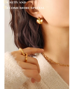 Close-up of gold-plated thick hoop earrings and spiral ring worn by elegant model
