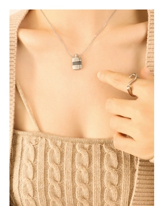 Détail d'un collier argenté avec pendentif bouilloire à rayures porté sur un mannequin