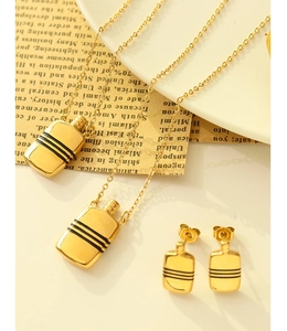 Détail du parure de bijoux dorés avec pendentifs flacon rayés sur journal rétro