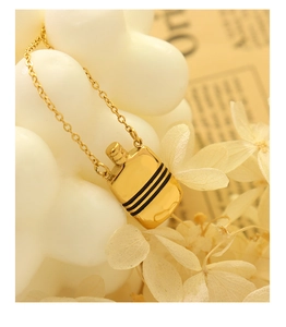 Détail macro d'un collier doré avec pendentif bouilloire orné de rayures noires élégantes