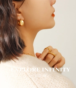 Close-up of a model wearing 18K gold plated C-shaped ball earrings and matching jewelry