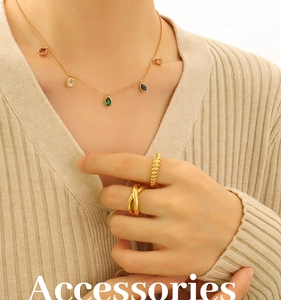 Close-up of gold necklace with colorful teardrop pendants and layered rings on model