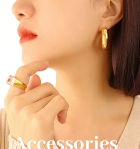 Detail of high-polish gold U-shaped earrings and ring with pink rectangular gemstone