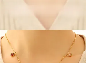 Close-up of golden beaded chain necklace with red and pink pear-cut zircon pendants