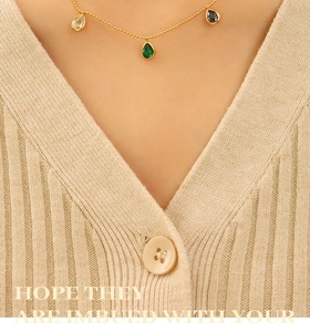 Detailed view of a gold bead chain necklace with three colorful teardrop zircon pendants