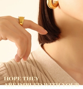 Macro detail of high-polish U-shape gold earrings and thick ring on female model