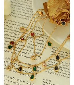 Macro detail of a vintage gold beaded necklace with colorful teardrop gemstone pendants