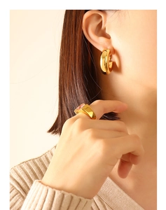 Detail of gold U-shaped hoop earrings and chunky ring set with pink gemstone