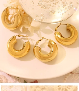 Macro shot of polished gold-plated titanium U-shaped hoop earrings on elegant lace decor