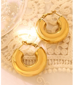 Close-up of polished golden U-shaped hoop earrings resting on delicate white lace