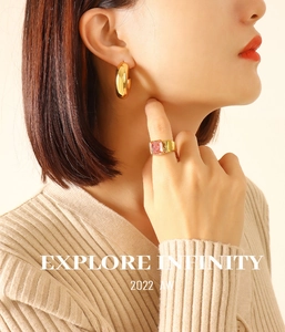 Detail of chunky gold U-shaped earrings and a ring with large rectangular pink stone