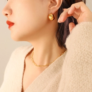 Minimalist C-shaped bead earrings and gold rope chain necklace worn by a fashion model