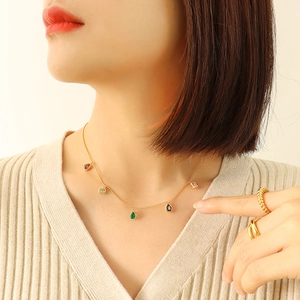 Golden necklace with colorful teardrop stones and textured rings on a model