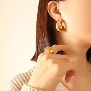 U-shaped gold-plated titanium earrings and pink gemstone ring on a female model
