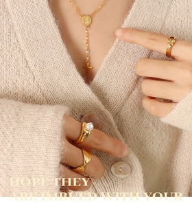 Detail of vintage gold layered necklace with cross pendant and pearl ring on model