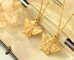 Close-up of 18k gold plated angel relief pendants with beaded chain on vintage box