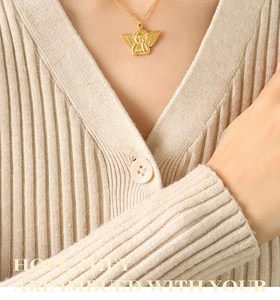 Detail of 18k gold plated angel pendant necklace with intricate wing textures on a sweater