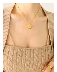 Detail of 18k gold angel pendant necklace and textured wide band ring on model