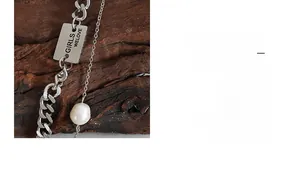 Close-up of titanium steel necklace with letter B tag and baroque freshwater pearl