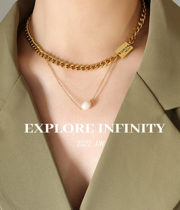 Detail of layered gold curb chain with baroque pearl and engraved square tag on model