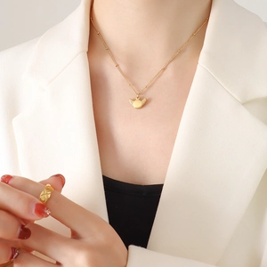 Minimalist gold wing pendant necklace and geometric textured ring on a model