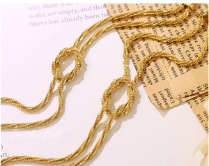 Detailed close-up of golden knotted chain bracelet with fine twisted metallic texture