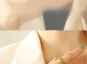 Detail of gold titanium ring with woven chain texture worn by a model in a suit
