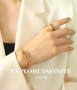 Detailed shot of gold knot bracelet and textured ring set on elegant model