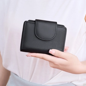 Close-up of black lychee grain leather wallet with snap closure and stitched details