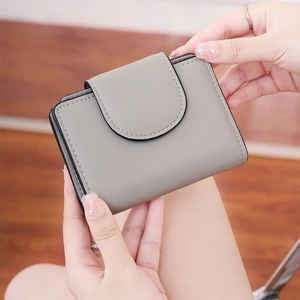 Close-up of a mini grey textured leather wallet held in hands to show compact size