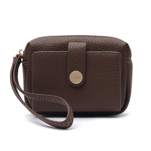 Detail of dark brown pebble leather wallet featuring a gold round buckle and wristlet strap