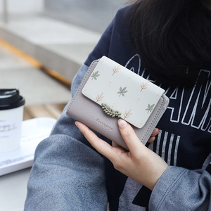 Close-up of a short PU leather wallet with leaf patterns and elegant metal buckle