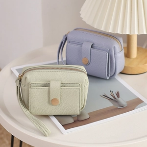 Litchi pattern PU leather coin purses with gold zippers and wrist straps on a white table